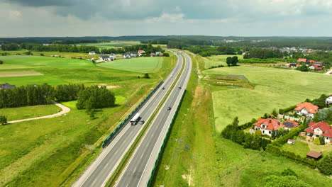 Luftaufnahme-Einer-Autobahn,-Die-Durch-Eine-Ländliche-Landschaft-Mit-Feldern-Und-Häusern-Verläuft