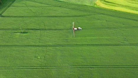 Aerial-view-of-a-crop-duster-spraying-a-green-field-with-tracks