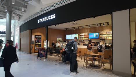 Gente-Haciendo-Cola-En-La-Cafetería-Starbucks-En-La-Zona-De-Salidas-Del-Aeropuerto-Charles-De-Gaulle-En-París,-Francia