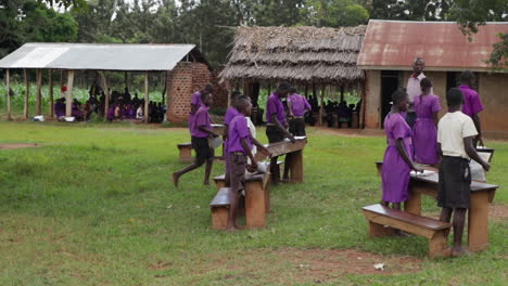 Children-attending-an-outdoor-class-in-Kampala,-Uganda-on-a-sunny-day,-outside-desks