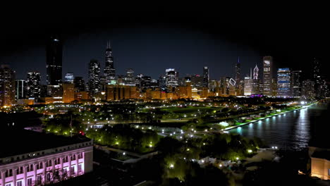 Disparo-De-Un-Dron-Elevándose-Frente-Al-Parque-Grant,-Durante-La-Noche-En-South-Loop,-Chicago