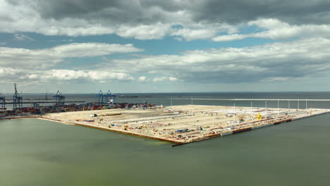 Aerial-view-of-a-large-industrial-port-area-under-a-cloudy-sky-in-Gdańsk,-Poland