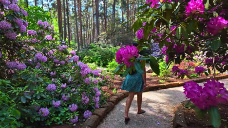 Woman-walking-inside-park-surrounded-by-flowers,-Mezaparks-in-Riga,-Latvia