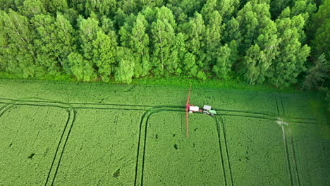 Aerial-view-of-a-crop-duster-spraying-a-field-adjacent-to-a-dense-forest