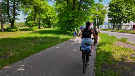 Cyclists-enjoying-a-sunny-day-on-a-tree-lined-path-in-Riga,-Latvia