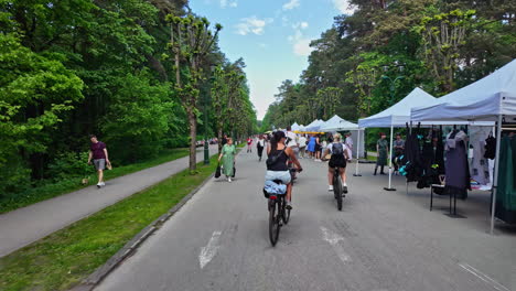 Cyclists-ride-through-Mežaparks-in-Latvia-during-a-lively-outdoor-market-event