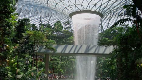 Jewel-Changi-Airport-Terminal-Monorail-Train,-Under-Glass-Dome,-Indoor-Waterfall-and-Tropical-Forest