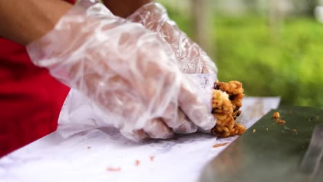 Close-up-of-street-food-vendor-hands-wrapping-food