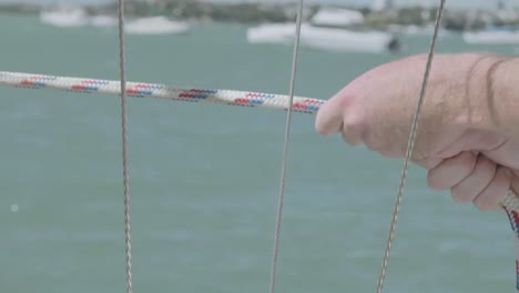 Wide-shot-of-cool-guy-with-sunglasses-clean-hitches-and-pulls-his-small-boat-to-wharf-in-waitemata-harbor