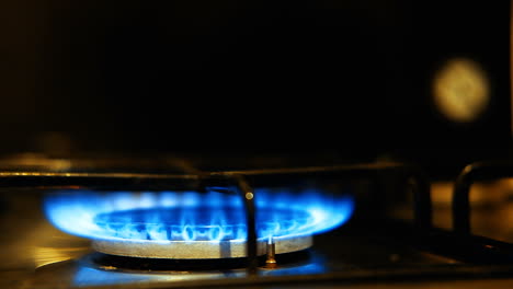 Close-up-of-a-blue-flame-that-lights-up-on-a-stove