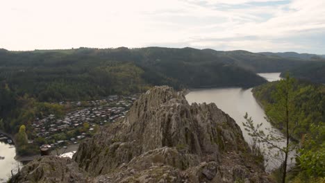 Panoramic-view-above-the-autmn-forest-and-the-water-reservoir-in-Thuringia-Germany-with-a-rock-in-the-foreground