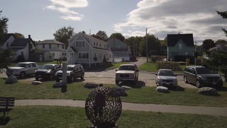 Aerial-Drone-Shot-Circling-Around-Woman-Taking-Photo-Of-Spherical-Sculpture-In-Rockland-Harbor-In-Maine