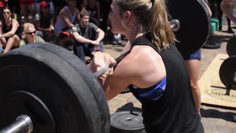 Mujeres-Jóvenes-En-Forma-En-Cuclillas-Usando-Una-Barra-Olímpica-Durante-Una-Competencia-De-Crossfit,-Entrenamiento-De-Fuerza-Para-La-Resistencia-Muscular,-Saludable-Y-Bueno-Para-Perder-Peso-Y-Desarrollar-Músculos-Y-Núcleos