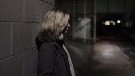 Girl-leans-against-a-wall-in-an-alley-at-night