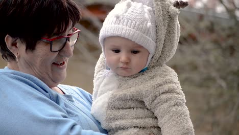 Grandmother-holding-her-grandson-outdoors-on-a-cold-winter-day-while-looking-very-blessed