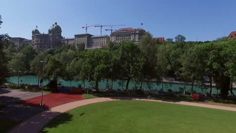 Flight-along-the-Aara-River-site-in-front-of-the-Federal-Palace-of-Switzerland,-House-of-Parliament,-Bern-the-capital-of-Switzerland-AERIAL-SHOT