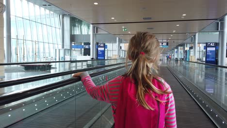 Helsinki,-Finlandia---Julio-De-2019:-Linda-Niña-Caucásica-Con-Mochila-En-Una-Pasarela-Móvil-En-El-Vestíbulo-Del-Aeropuerto-De-Helsinki