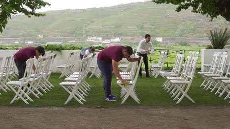 Gruppe-Von-Menschen,-Die-Nasse-Stühle-Reinigen,-Die-Im-Garten-Für-Eine-Hochzeitszeremonie-In-Quinta-Da-Pacheca,-Lamego,-Viseu,-Portugal-Aufgestellt-Sind