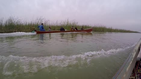 Vista-En-Tándem-De-Un-Barco-Motorizado-Tradicional-En-Las-Marismas-Del-Sur-De-Irak-Con-El-Anciano-Tribal-A-Bordo-Vistiendo-Ropa-Tradicional