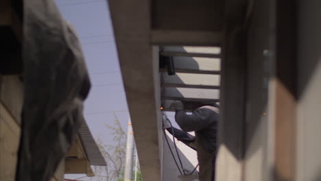 Man-welding-a-metal-vigge-on-the-roof-of-a-house,-in-4k-at-60fps