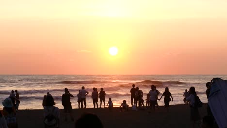 Strand-In-Taiwan-Mit-Leuten,-Die-Vom-Ufer-Aus-Den-Sonnenuntergang-Betrachten