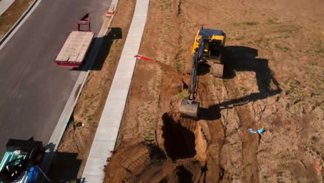 A-drone-shot-of-a-construction-worker-digging-a-hole-in-the-morning-for-the-starting-of-a-new-house-in-the-suburbs