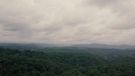 Drone-flying-up-over-forest,-trees,-farmland,-and-under-clouds-in-the-Smoky-Mountains,-USA-for-a-pretty,-overcast-aerial-footage