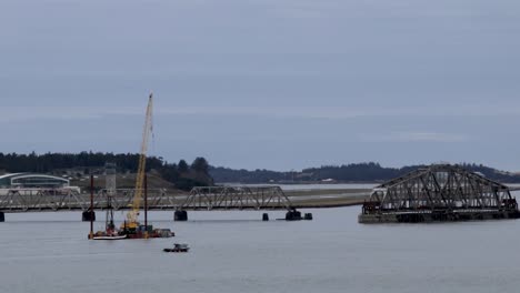 Ein-Kran-Auf-Einem-Schwimmer-Wird-Von-Einem-Schlepper-Geschoben,-Um-An-Einer-Drehbrücke-Zu-Arbeiten