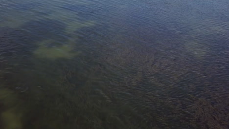 Low-aerial-flyover-of-man-and-woman-on-fishing-boat-in-shallow-water