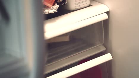 African-American-woman's-hand-putting-food-back-into-refrigerator
