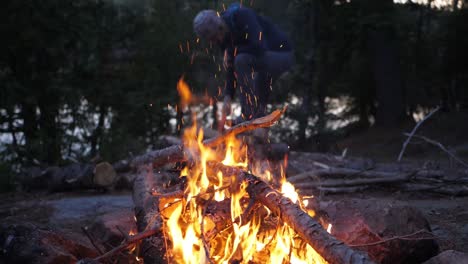 Camp-fire-with-man-cutting-fire-wood-slow-motion-move-in