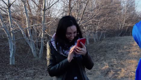 Dark-haired-girl-takes-photo-of-young-boy-on-mobile-phone-and-smiles