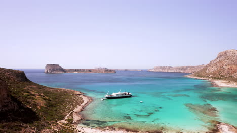 Toma-Aérea-Desde-Una-Plataforma-Rodante-Que-Muestra-A-Los-Pasajeros-Subiendo-A-Un-Barco-En-La-Playa-De-Balos-En-Creta,-Grecia,-En-Un-Hermoso-Día-Soleado.