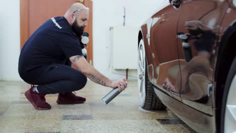 Car-cleaning-professional-applies-spray-to-car-tyre-during-detailing-procedure