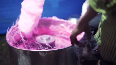 A-Pair-of-hands-making-cotton-candy-in-a-spinning-pink-fluffy-maker-in-slow-motion