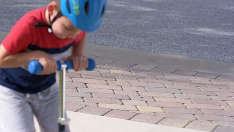 Kleiner-Junge,-Der-Auf-Einem-Roller-Auf-Dem-Bürgersteig-Fährt-Und-Spaß-Hat