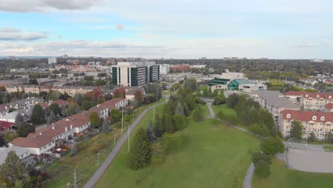 Aerial-footage-going-towards-a-lot-of-large-buildings-with-a-pond-and-buses-and-cars-in-the-distance