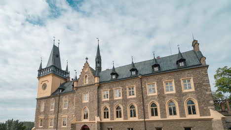 renaissance-palace-with-puffy-clouds-rushing-over-turquoise-sky-and-reflecting-in-it's-windows,-time-lapse