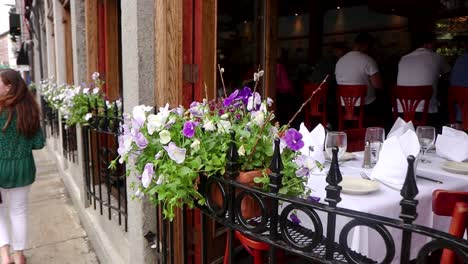 Walking-panning-shot-of-a-bouquet-of-purple-and-white-flowers-on-the-fence-of-an-outdoor-seating-venue-at-a-restaurant