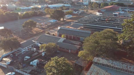 Un-Dron-Tirado-Hacia-Atrás-De-Edificios-Industriales-En-Las-Afueras-De-Bulawayo,-Zimbabwe-Al-Atardecer