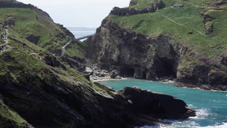 Gente-De-Vacaciones-Caminando-Sobre-Un-Acantilado-A-Lo-Largo-Del-Camino-Que-Conduce-A-Las-Ruinas-Del-Castillo-De-Tintagel-Y-Al-Puente-A-La-Isla-En-Cornualles