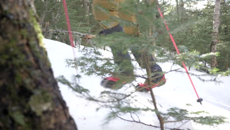 Un-Hombre-Sube-Una-Empinada-Pendiente-Nevada-En-El-Bosque-Con-Bastones-De-Trekking-En-Cámara-Lenta