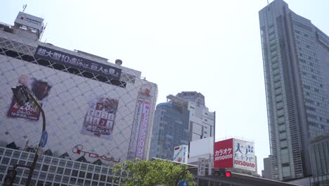 Famous-Shibuya-crossing-in-Tokyo-on-ground-level-with-tourists-and-locals-walking,-Japan