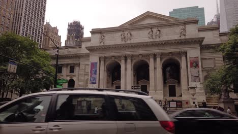 Lapso-De-Tiempo-En-Movimiento-De-La-Entrada-De-La-Biblioteca-Pública-De-Nueva-York-Con-El-Tráfico-De-La-Quinta-Avenida-En-Primer-Plano-En-Una-Lluviosa-Mañana-De-Verano