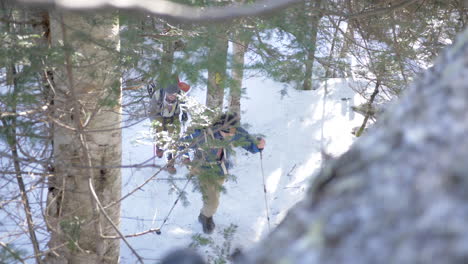 High-Angle-Shot-of-Two-Men-Hiking-Up-a-Snowy-Mountain-in-the-Woods-of-New-Hampshire,-Slow-Motion