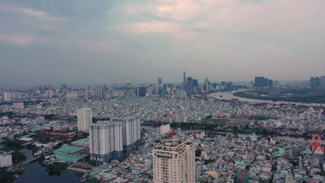 Abendlicher-Drohnenflug-über-Bezirk-7-Von-Ho-Chi-Minh-Stadt-Mit-Mittlerer-Bis-Hoher-Wohndichte-Und-Blick-Auf-Bezirk-4-Und-Die-Skyline-Der-Stadt