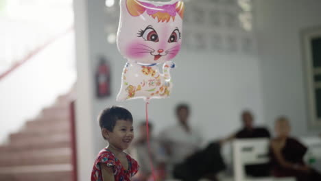 happy-burmese-child-playing-with-a-kitten-balloon