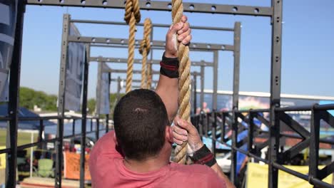 Un-Hombre-Fuerte,-Atlético-Y-En-Forma-Haciendo-Una-Escalada-De-Cuerda-Militar-Para-El-Entrenamiento-De-Fuerza-Muscular-Y-Resistencia,-Popular-En-Todas-Las-Fuerzas-Armadas,-Programas-De-Entrenamiento-De-Cursos-Cruzados-Y-De-Asalto