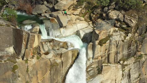 Drone-footage-of-man-standing-on-stop-of-Feather-Falls-near-Oroville,-California-in-the-Plumas-National-Forest