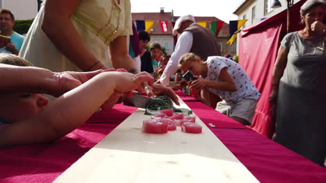 Slow-motion-of-peasant-commoners-cutting-sweets-for-people-and-children-gathered-around-the-table,-medieval-reenactment,-Preludij-festival-in-Slovenj-Gradec-slovenia